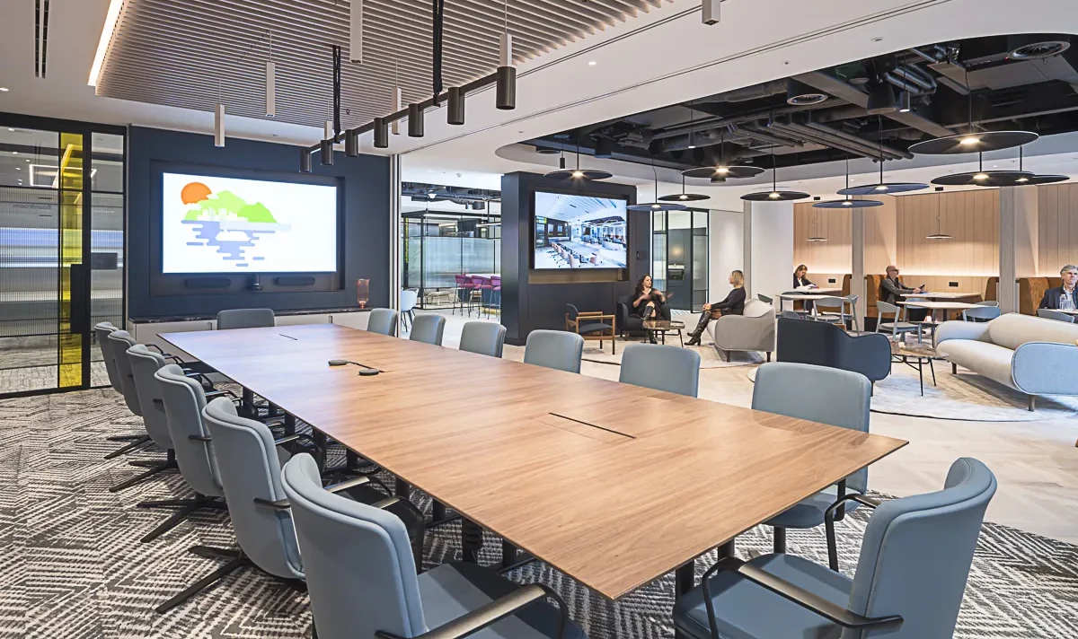 Savills Investment Management office furniture, meeting area large conference desk with blue chairs large screen and open plan office in the background.